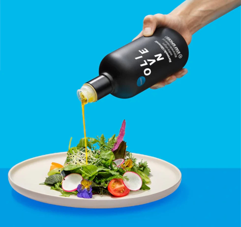 Extra Natives STAY SPICED ! Olivenöl wird aus der schwarzen Flasche über einen frischen Salat gegossen