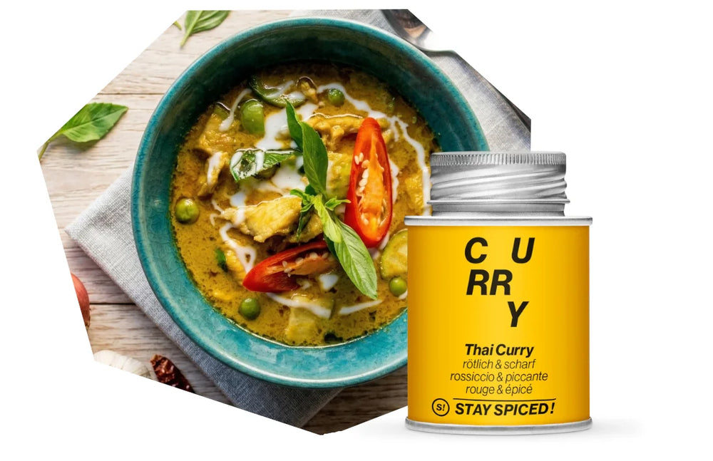 Eine Schüssel mit einem frisch zubereiteten scharfen Thai-Curry, garniert mit frischen Kräutern und Chili, neben einer Dose STAY SPICED ! Curry