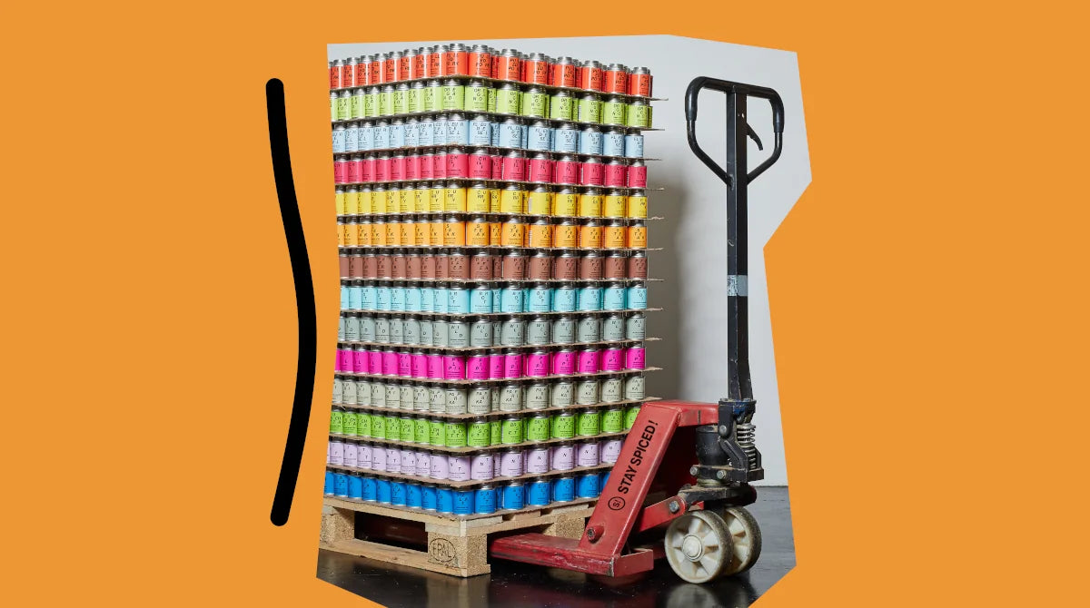 Ein roter Hubwagen mit einer voll beladenen Europalette bunter STAY SPICED! Gewürzdosen. Die offizielle Schweizer Vertretung und Gewürzshop für Haushalt und Gastronomie.