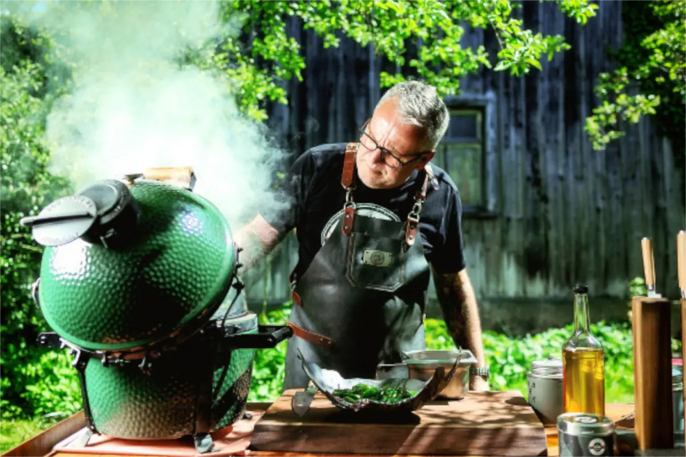 Grillmeister Tom Heinzle reibt lächelnd ein Stück rohes Fleisch mit STAY SPICED! Grillgewürzen im Freien ein online kaufen bei chefkoch-gewürze Schweiz